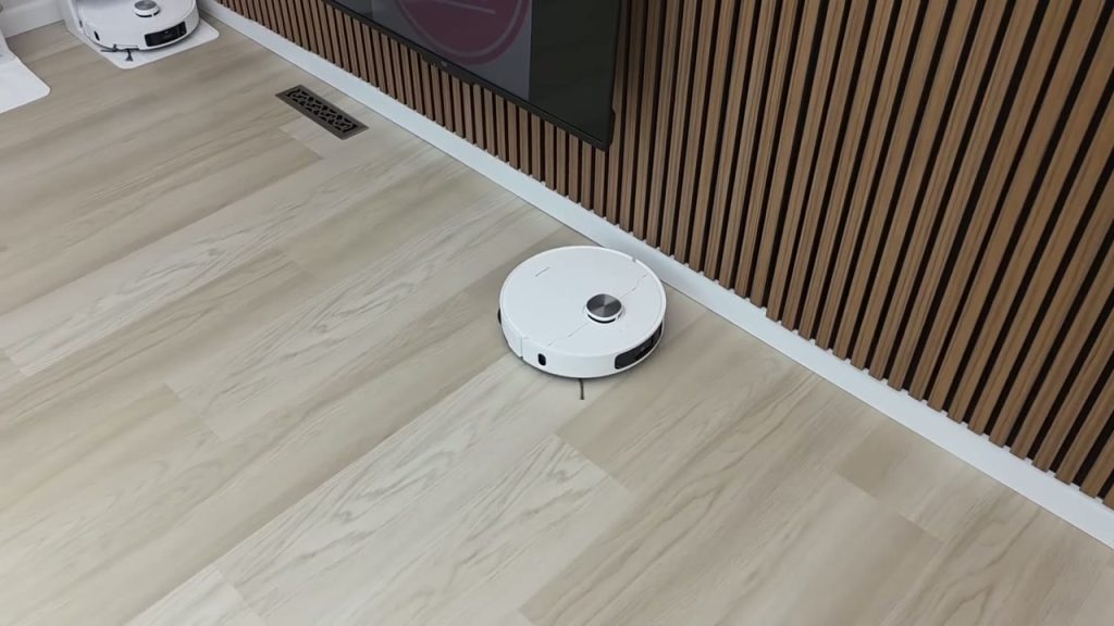 Dreame L10s Ultra Gen 2 städar längs en vägg på ett ljust trägolv