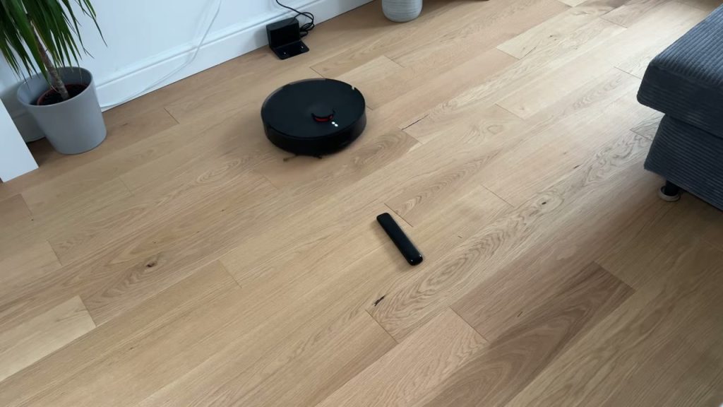 Xiaomi Robot Vacuum S20+ kör runt en fjärrkontroll på trägolvet
